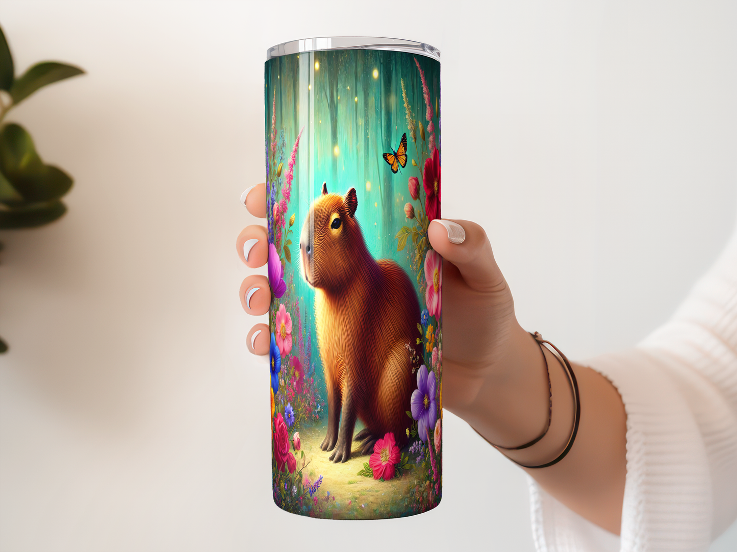 A person's hand holding a cylindrical container with a colorful, whimsical illustration of a capybara surrounded by flowers, butterflies, and a forest-like setting.