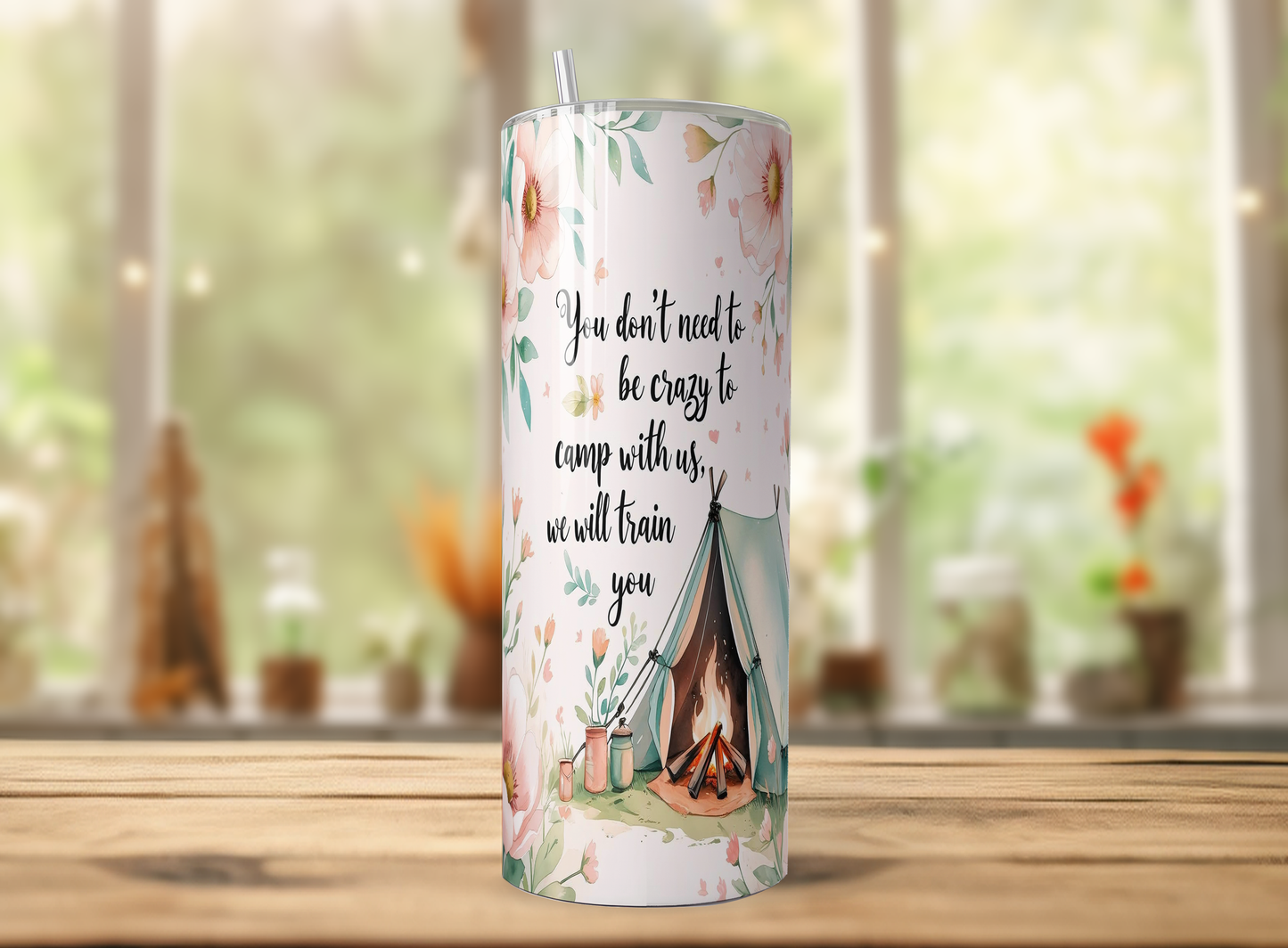 A cylindrical tumbler with a printed design on it, featuring a camping scene with a tent and campfire.