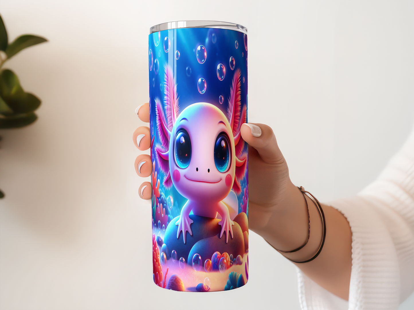 A person's hand holding a colorful, cartoonish cup with a design featuring a cute, smiling amphibian-like creature surrounded by bubbles and underwater elements.