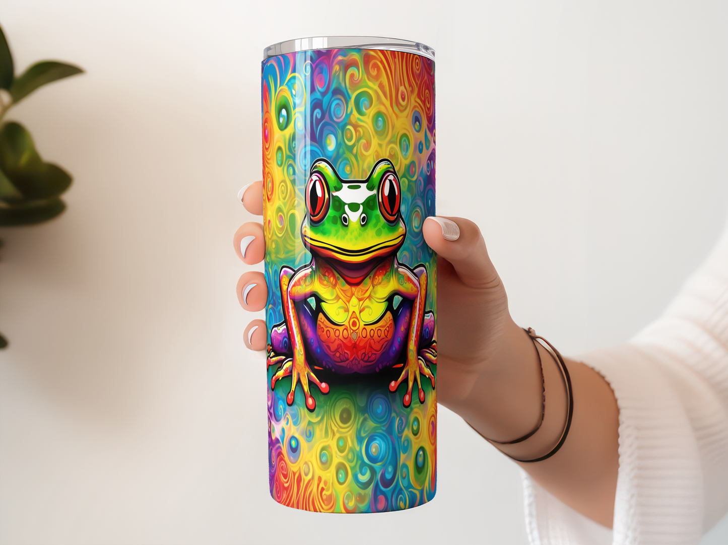 A person's hand holding a colorful, rainbow-colored frog-themed tumbler or cup.