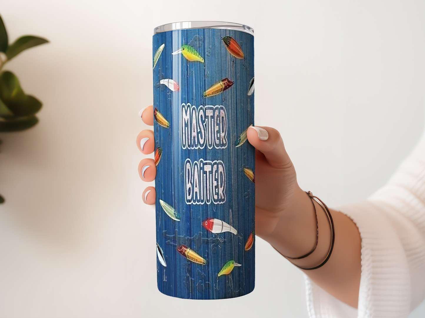 A person's hand holding a blue tumbler with a pattern of fish on it, and the text "MASTER CRAFT" printed on the side of the tumbler.