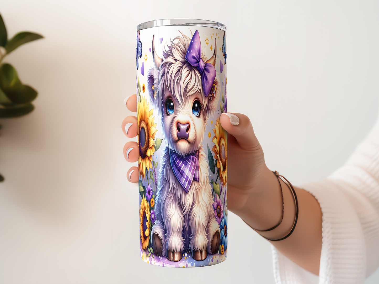 A person's hand holding a cylindrical container with a colorful illustration of a cow or sheep on it, surrounded by flowers and other natural elements.