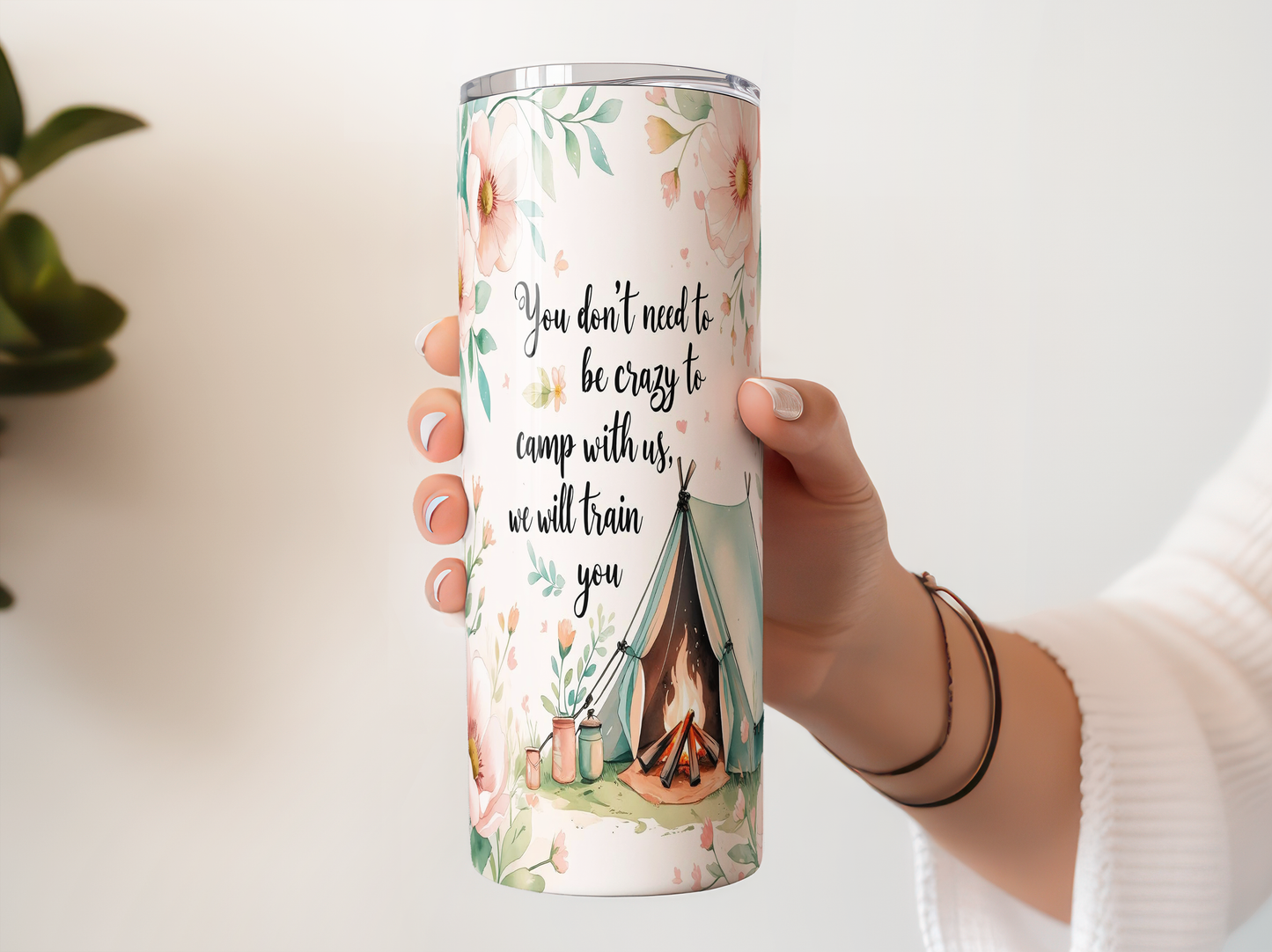 A person's hand holding a tall, cylindrical container with a floral design and text printed on it.