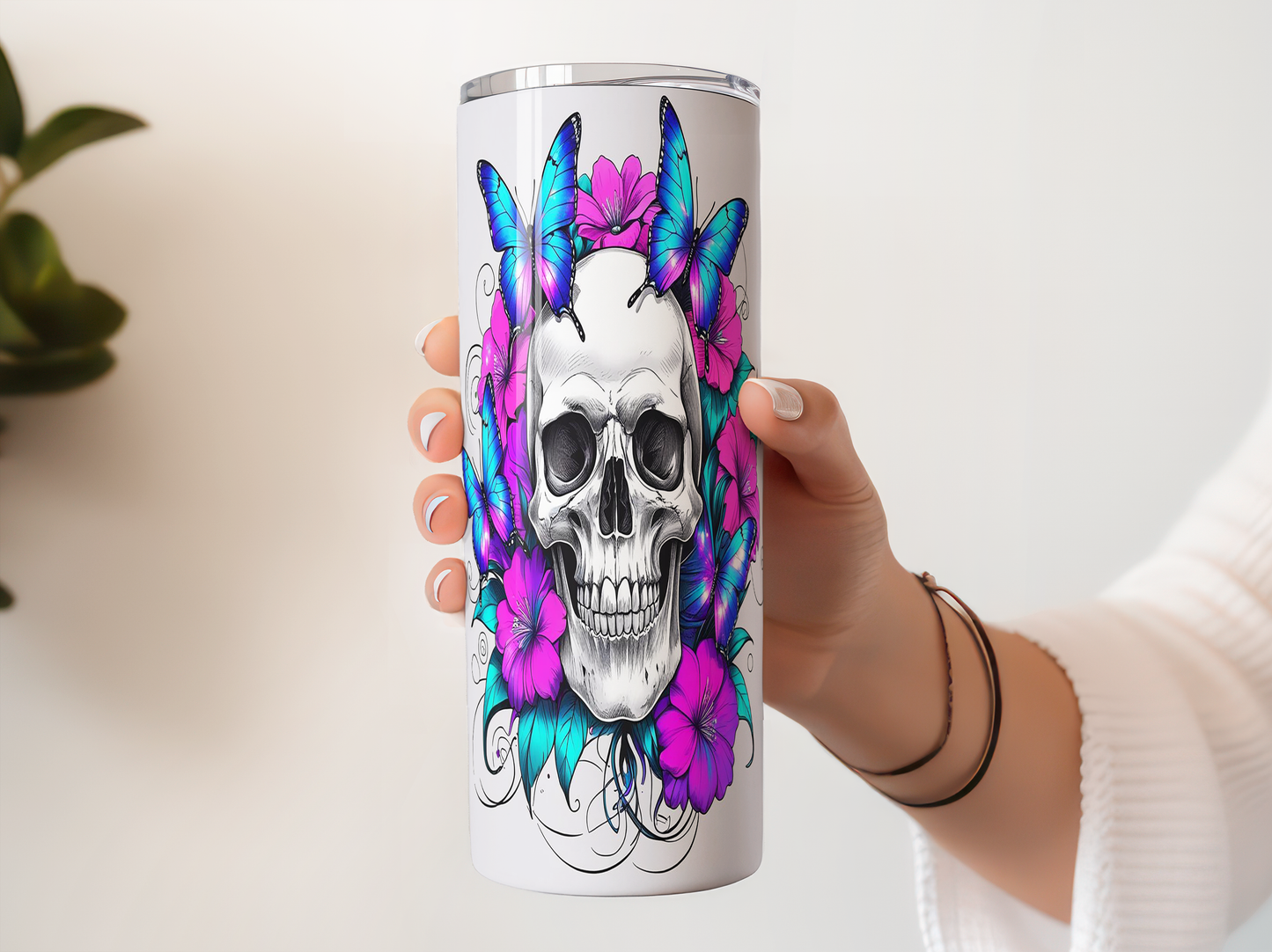 A person's hand holding a white cylindrical container with a colorful design featuring a skull surrounded by butterflies and flowers.