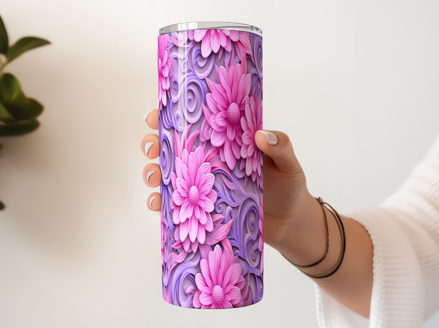 A person's hand holding a tall, cylindrical container with a vibrant floral pattern in shades of pink and purple.