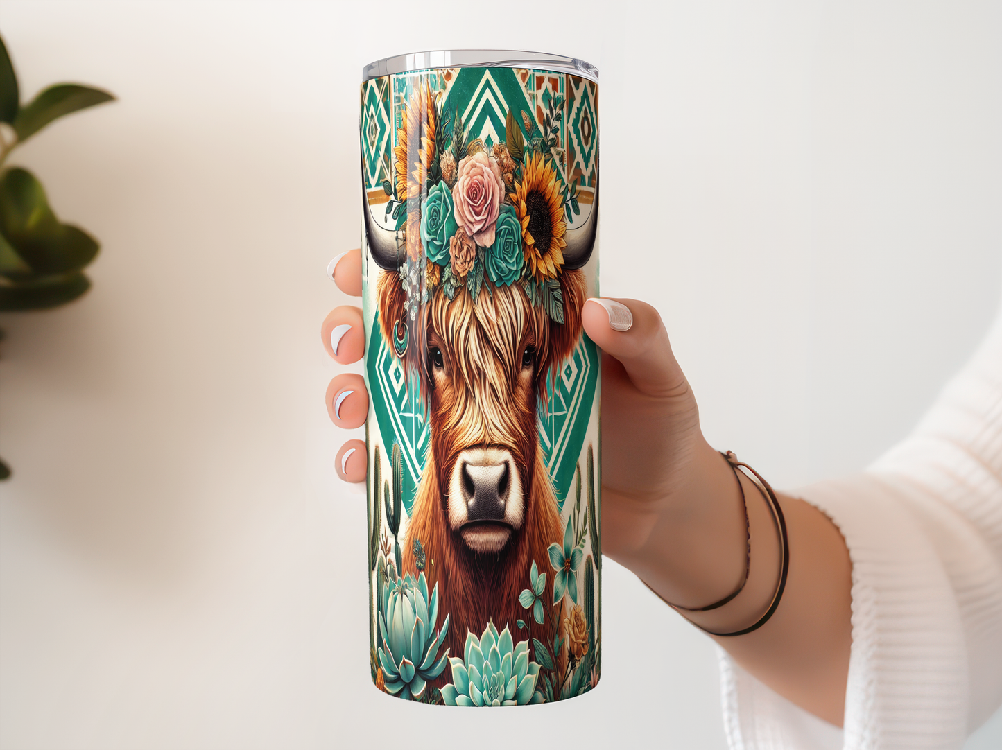 A person's hand holding a tall, cylindrical container with a colorful, artistic design featuring a cow's face surrounded by various floral and geometric elements.