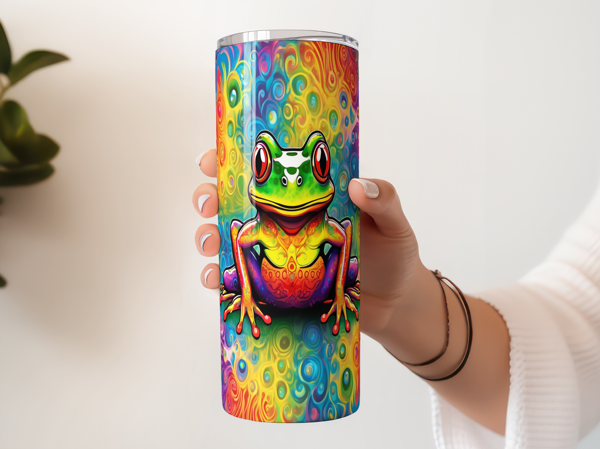 A person's hand holding a colorful, rainbow-colored frog-themed tumbler or cup.